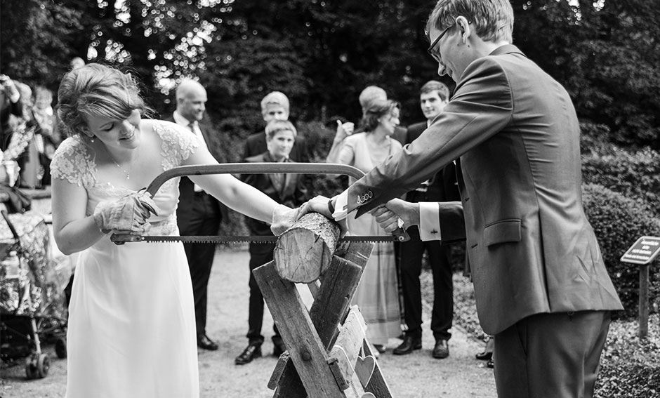 Hochzeitsfoto Hochzeitsspiele Tradition Holzstamm sägen Brautpaar Freude Hochzeitsfeier Berlin