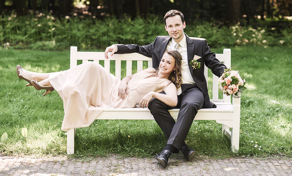 Hochzeitsfoto Brautpaar im Grünen Park auf Bank
